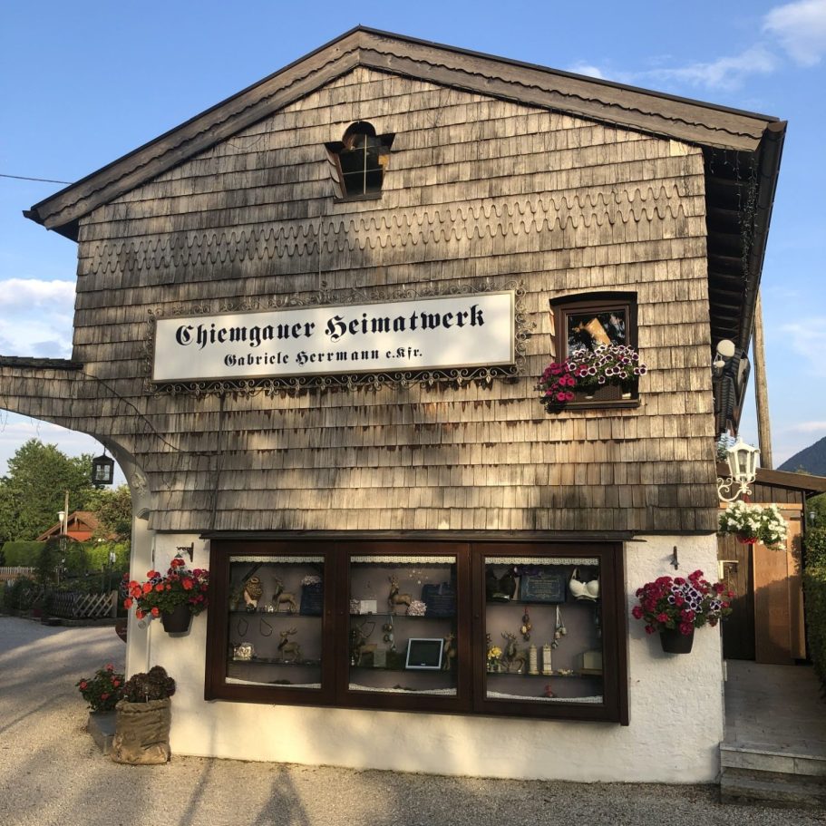 Holzverkleidetes Gebäude mit blühenden Blumenkästen und einem Schaufenster.