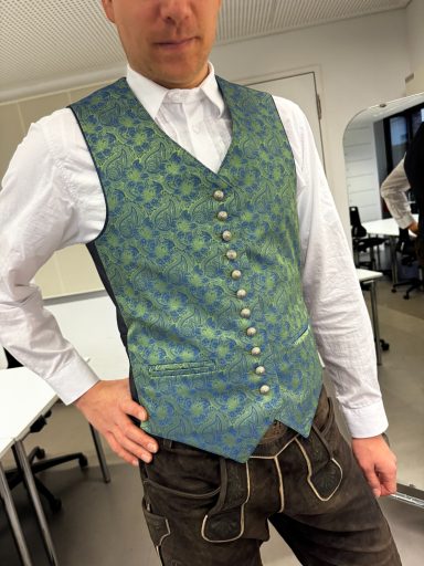 Elegante grüne Weste mit Muster, kombiniert mit einem weißen Hemd und dunkler Hose.