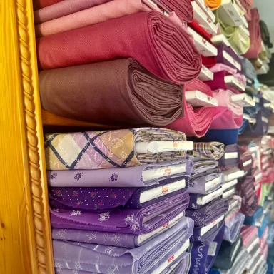 Bunte Dirndlstoffe und Trachtenstoffe  in Regalen, sortiert nach Farbe und Größe.