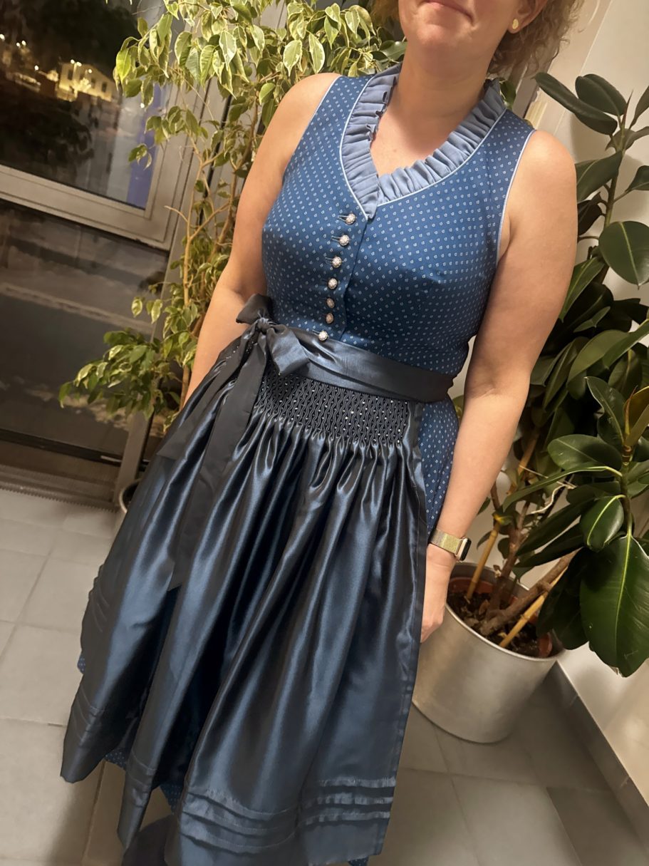 Frau in einem ärmellosen, blauen Kleid mit Knöpfen und tailliertem Schnitt.