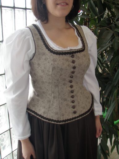 Frau in traditioneller Tracht mit weißem Shirt und brauner Rock.