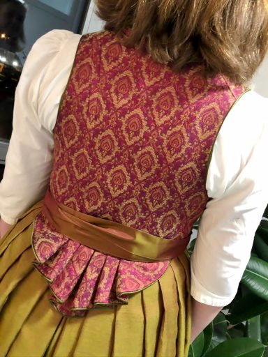 Rückansicht eines traditionellen Kleidungsstücks mit buntem Muster und Gürtel.
