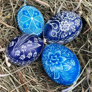 Blaue Ostereier mit filigranen weißen Mustern auf Heu arrangiert.