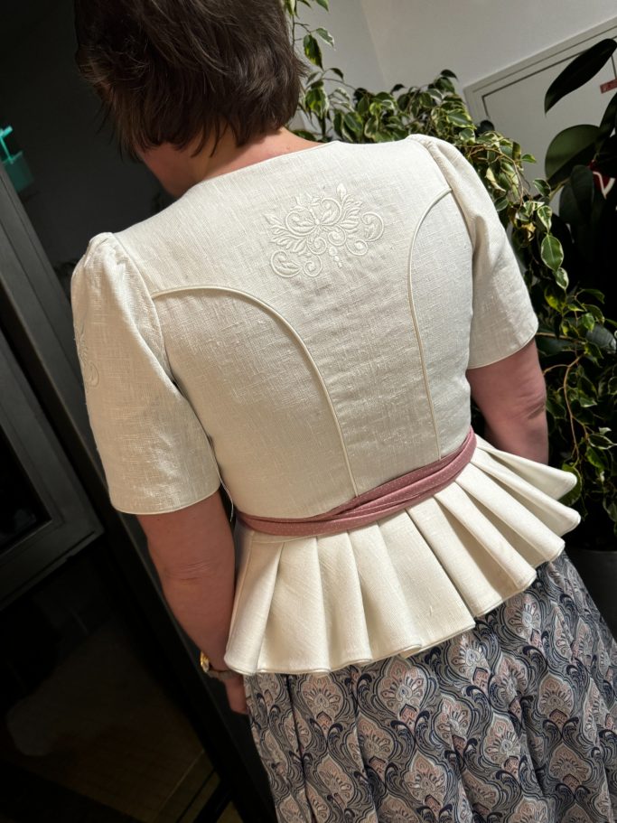 Frau von hinten in einem eleganten, weißen Oberteil mit Rüschensaum.